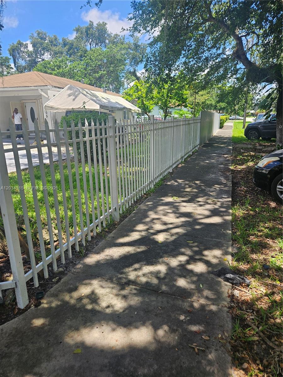 A white metal fence runs along a concrete sidewalk next to a single-story house — 1905 NW 113th Ter, Miami FL 33167, MIAMI, FL
