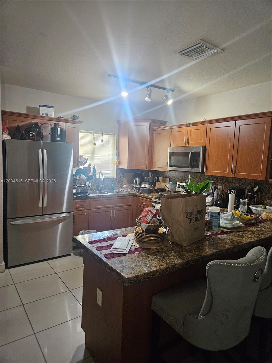 This kitchen features wood cabinets, granite countertops, stainless steel appliances, and a central island — 1905 NW 113th Ter, Miami FL 33167, MIAMI, FL