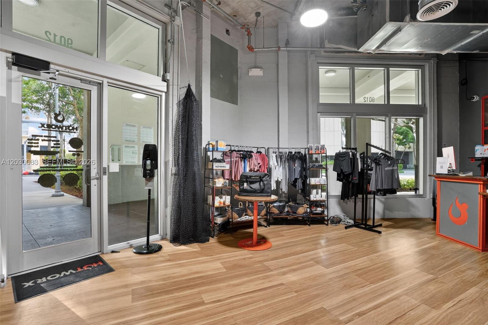 A retail space features wood-look flooring, clothing racks, a front desk, and glass entry doors — 9012 S Dadeland Blvd, Miami FL 33156, MIAMI, FL