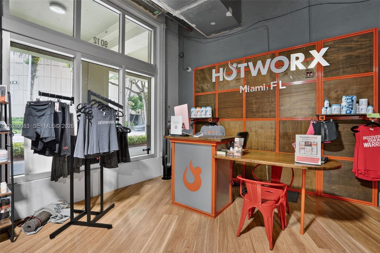 A reception area with a branded desk, clothing racks, and wood-look flooring — 9012 S Dadeland Blvd, Miami FL 33156, MIAMI, FL