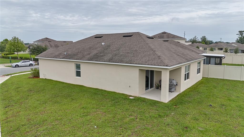 An exterior view of the back of a beige house with a covered patio — 1679 AURORA RIDGE DRIVE, ZELLWOOD, FL