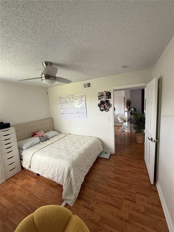 A bedroom features a bed, a white dresser, wood-look flooring, and a doorway to another room — 355 LAKEPOINTE DRIVE UNIT 304, ALTAMONTE SPRINGS, FL