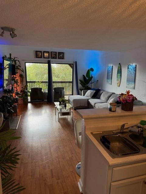 A living room with wood-look flooring, a sectional sofa, and a sliding glass door balcony — 355 LAKEPOINTE DRIVE UNIT 304, ALTAMONTE SPRINGS, FL