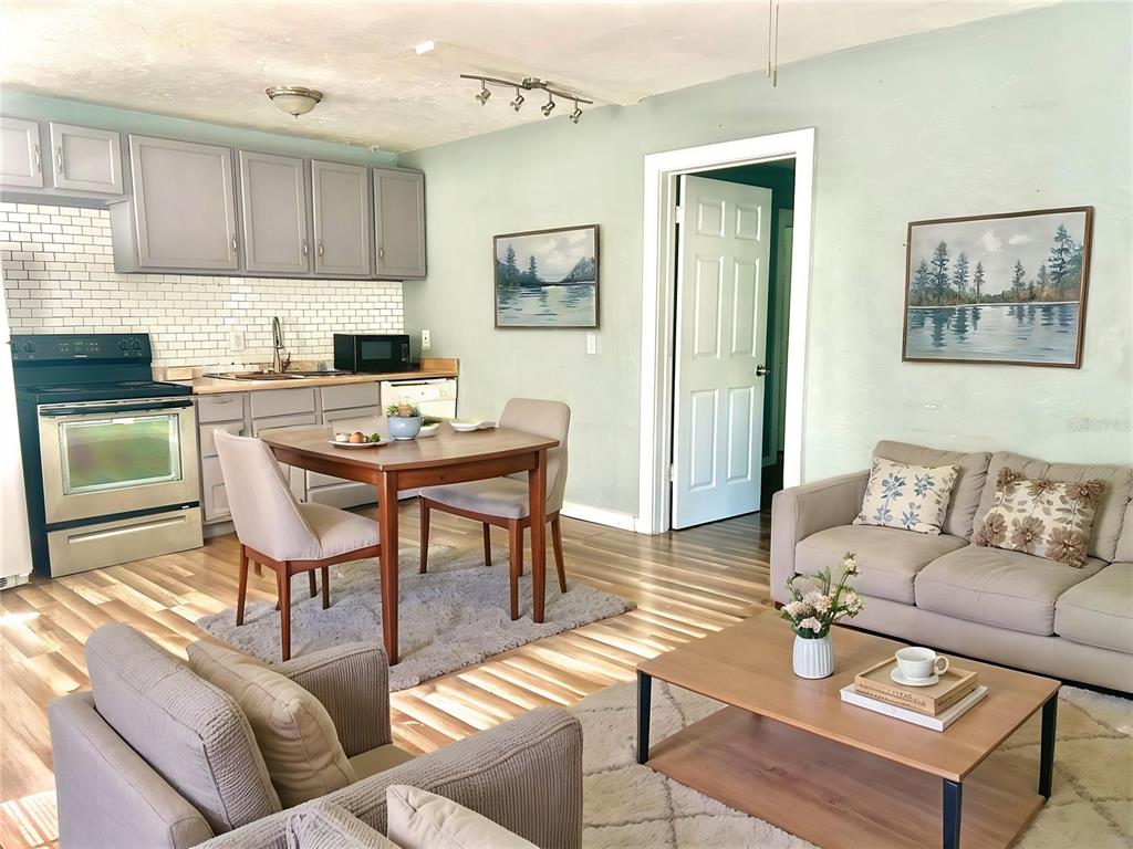 An open-concept kitchen and living area with light gray cabinets, wood flooring, and neutral furniture — 731 FLORENCE STREET, DAYTONA BEACH, FL