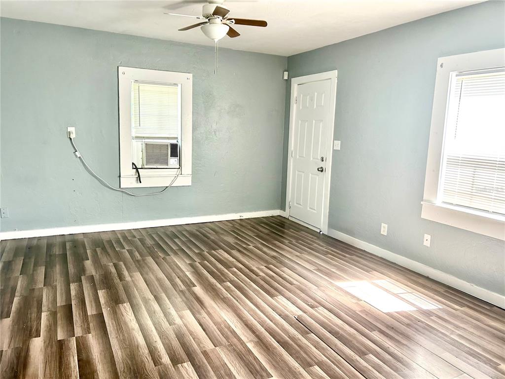 An empty room features light blue walls, wood-look flooring, a ceiling fan, and two windows — 731 FLORENCE STREET, DAYTONA BEACH, FL