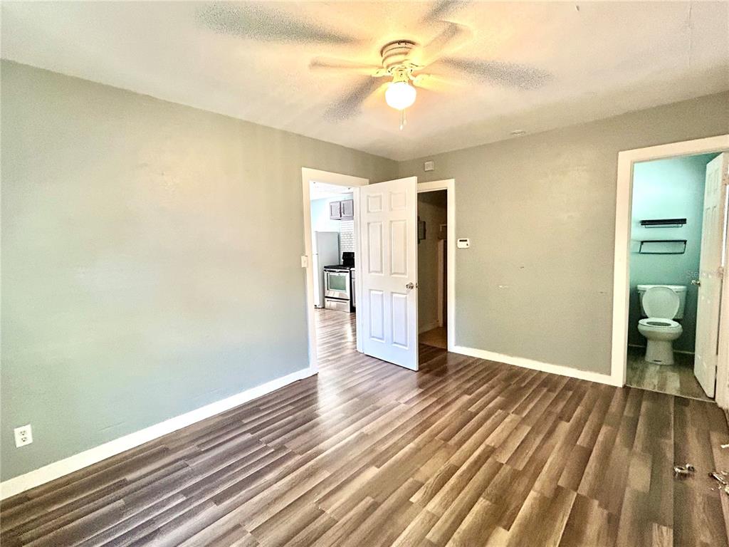 A room with wood-look flooring, a ceiling fan, and doorways leading to a kitchen and bathroom — 731 FLORENCE STREET, DAYTONA BEACH, FL
