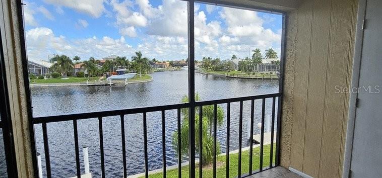 A screened-in balcony overlooks a canal with houses and a boat in the distance — 3768 BAL HARBOR BOULEVARD UNIT 4, PUNTA GORDA, FL