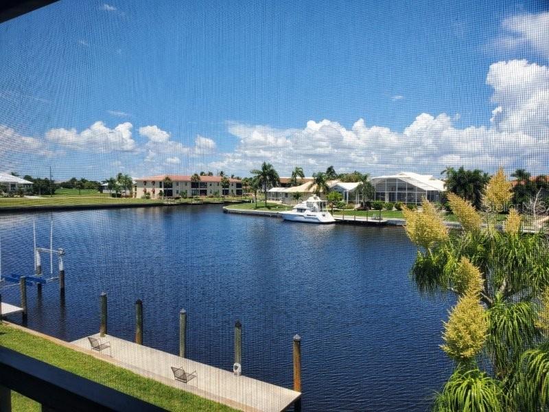 A view of a canal with a boat dock and residential buildings from a screened balcony — 3768 BAL HARBOR BOULEVARD UNIT 4, PUNTA GORDA, FL
