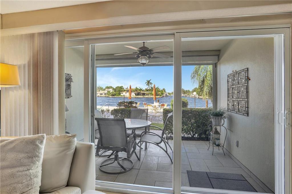 A view from a living room through sliding glass doors to a patio overlooking water — 505 N Riverside Drive # 4, Pompano Beach FL 33062, POMPANO BEACH, FL