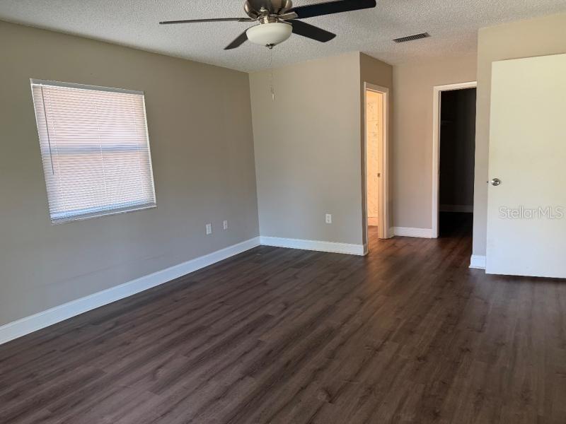 An empty bedroom features wood-look flooring, a ceiling fan, and two doorways — 3260 MARY LANE, MOUNT DORA, FL