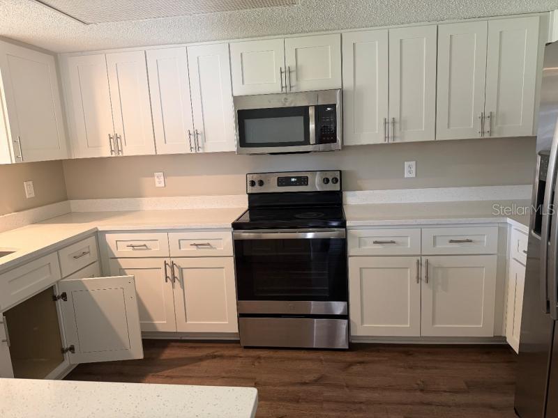 A kitchen features white shaker cabinets, stainless steel appliances, and light-colored countertops — 3260 MARY LANE, MOUNT DORA, FL