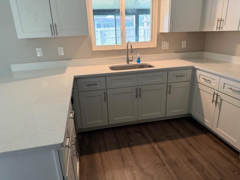 A kitchen features white shaker cabinets, light quartz countertops, a stainless steel sink, and flooring — 3260 MARY LANE, MOUNT DORA, FL