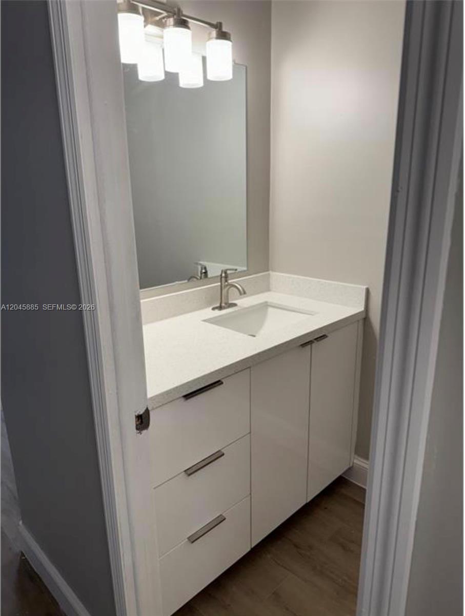 A bathroom features a white vanity with a quartz countertop, a mirror, and light fixtures — HOMESTEAD, FL