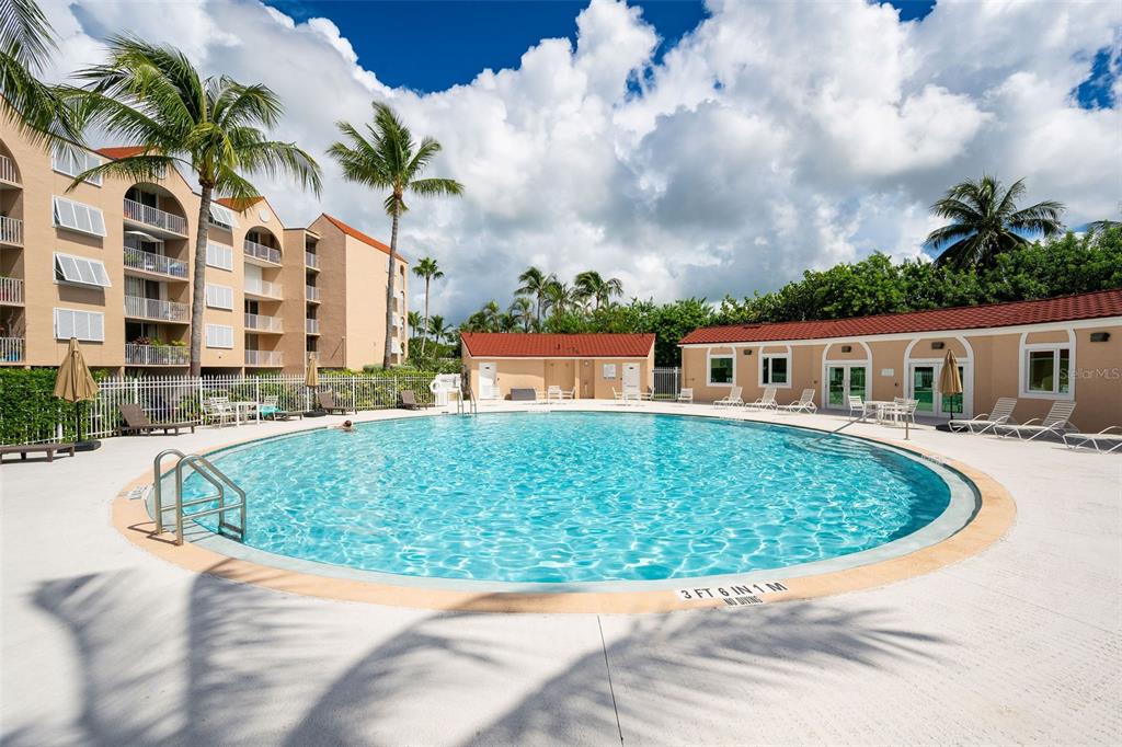 A circular swimming pool sits in front of a multi-story apartment building and clubhouse — 3930 S ROOSEVELT BOULEVARD UNIT S303, KEY WEST, FL