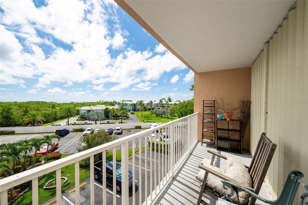 A balcony with a white railing overlooks a parking lot, palm trees, and the ocean — 3930 S ROOSEVELT BOULEVARD UNIT S303, KEY WEST, FL