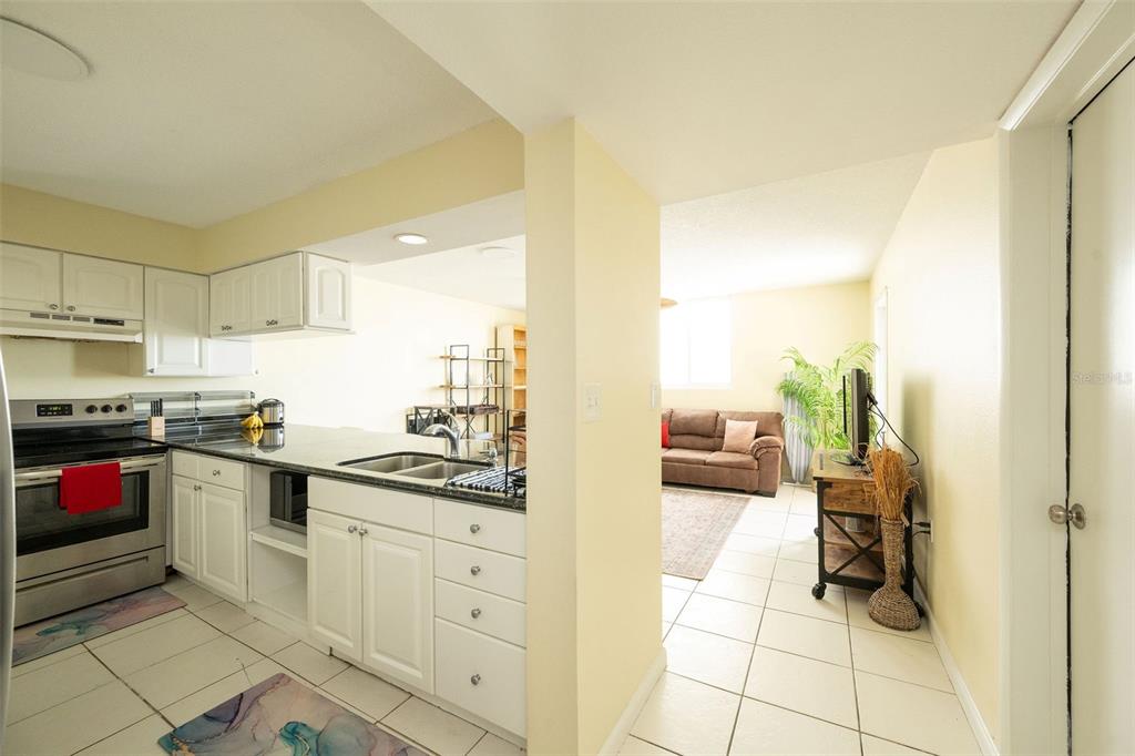 A kitchen with white cabinets and granite countertops opens into a living room with tile — 3930 S ROOSEVELT BOULEVARD UNIT S303, KEY WEST, FL