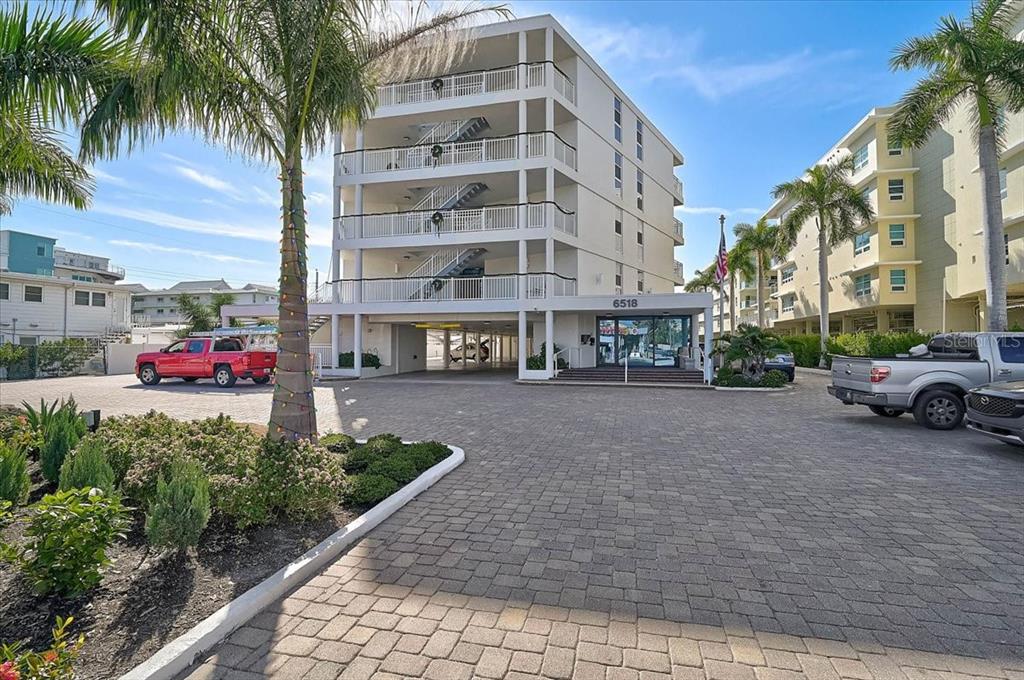 A multi-story apartment building with a paved parking area and palm trees in front — 6518 MIDNIGHT PASS ROAD UNIT 309, SIESTA KEY, FL