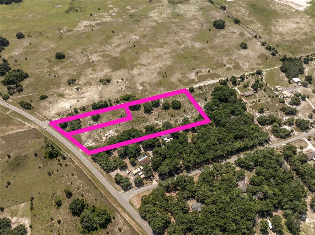 An aerial view shows a vacant, rectangular plot of land outlined in bright pink — 2034 S US 301 HIGHWAY, SUMTERVILLE, FL