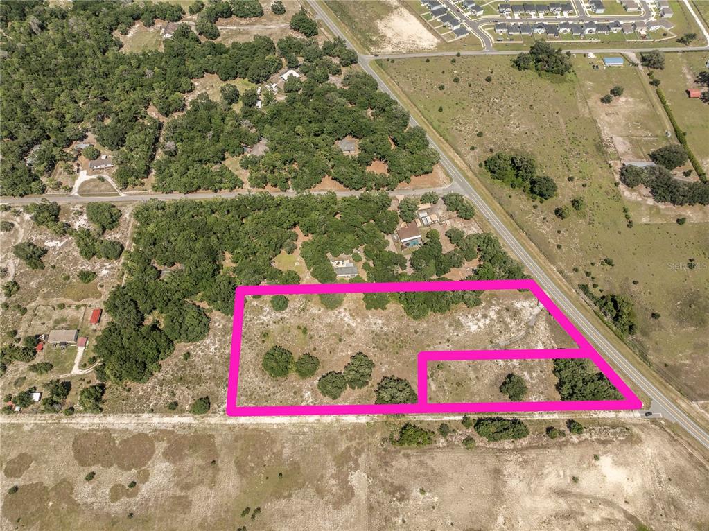 An aerial view shows a vacant, partially wooded lot outlined in pink near a road — 2034 S US 301 HIGHWAY, SUMTERVILLE, FL