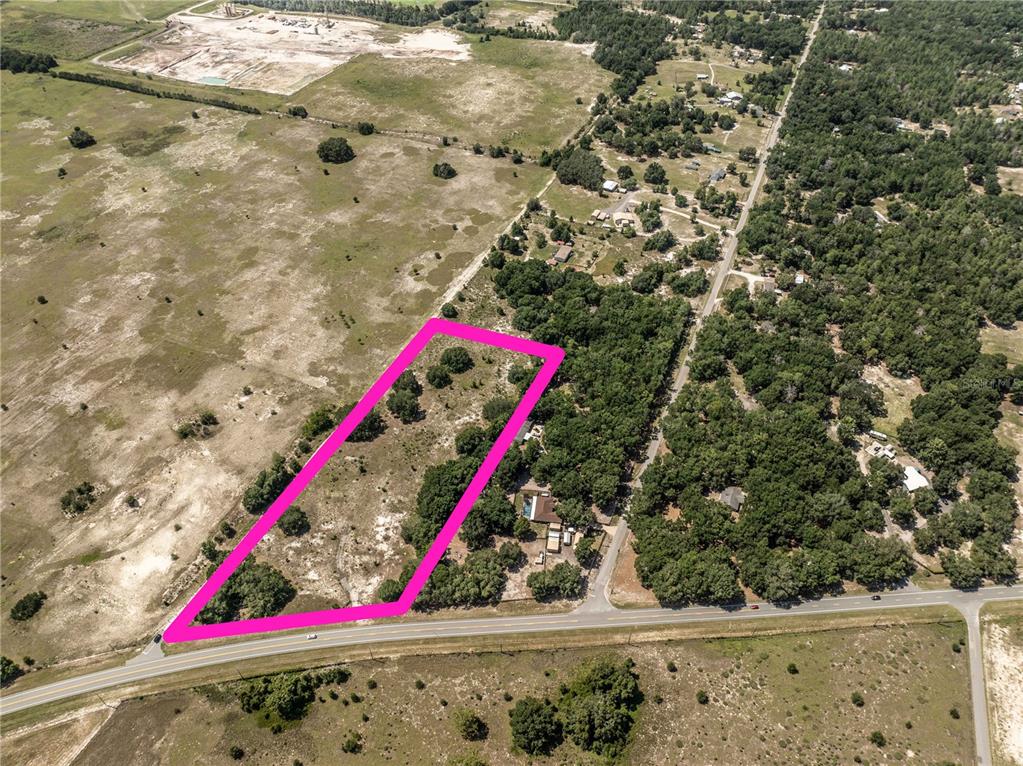 An aerial view shows a vacant, rectangular plot of land outlined in bright pink — 2034 S US 301 HIGHWAY, SUMTERVILLE, FL
