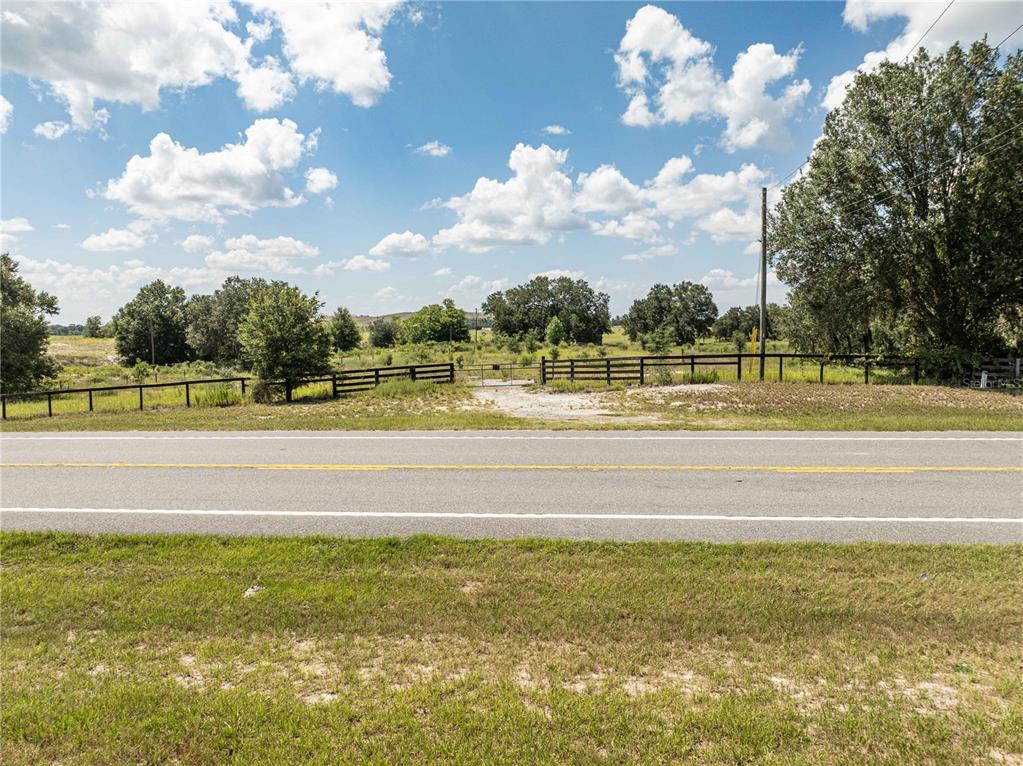 A paved road runs in front of a fenced rural property with trees and grass — 2034 S US 301 HIGHWAY, SUMTERVILLE, FL