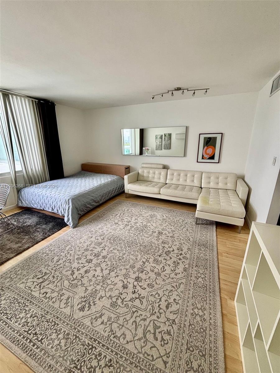 A studio apartment features a bed, a white sectional sofa, and a large patterned rug — 1000 West Ave # 822, Miami Beach FL 33139, MIAMI BEACH, FL