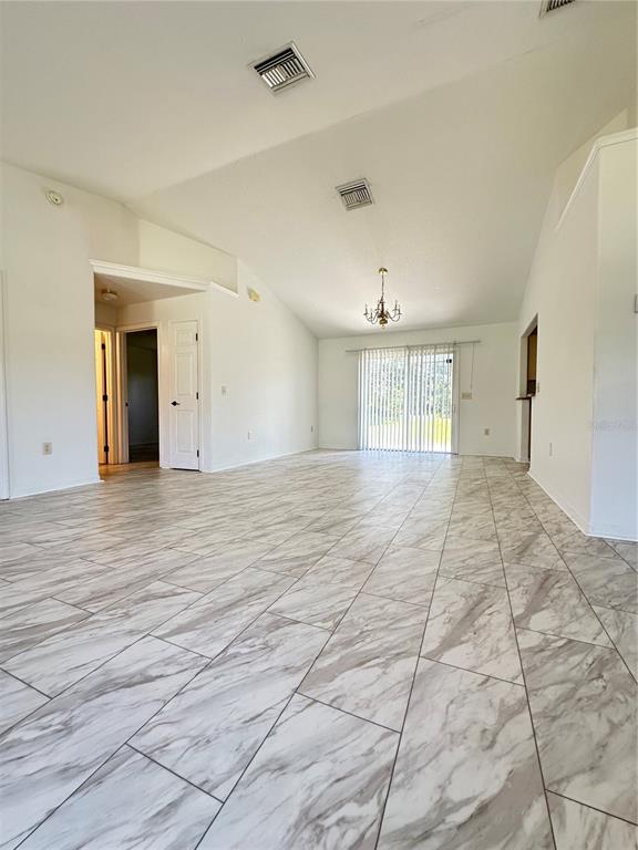 A bright, open-concept living area features vaulted ceilings, white walls, and marble-patterned tile flooring — 3142 SW 132ND LANE, OCALA, FL
