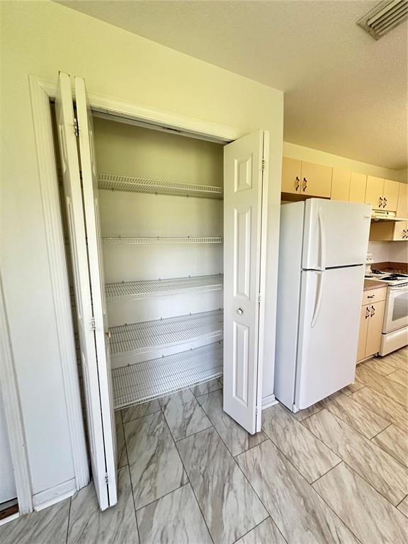 A kitchen features a white pantry with wire shelving next to a white refrigerator — 3142 SW 132ND LANE, OCALA, FL