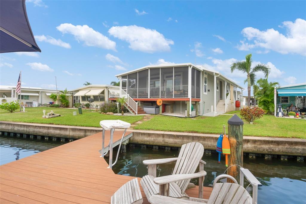 A wooden boat dock with a boat lift, patio furniture, and an umbrella on water — 6825 MOUNT ORANGE DRIVE NE UNIT 390, ST PETERSBURG, FL