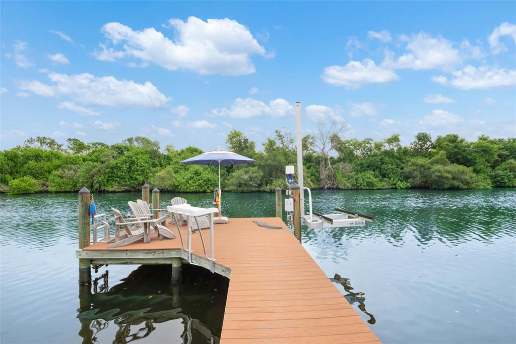 A waterfront home with a screened porch and deck sits behind a wooden boat dock — 6825 MOUNT ORANGE DRIVE NE UNIT 390, ST PETERSBURG, FL