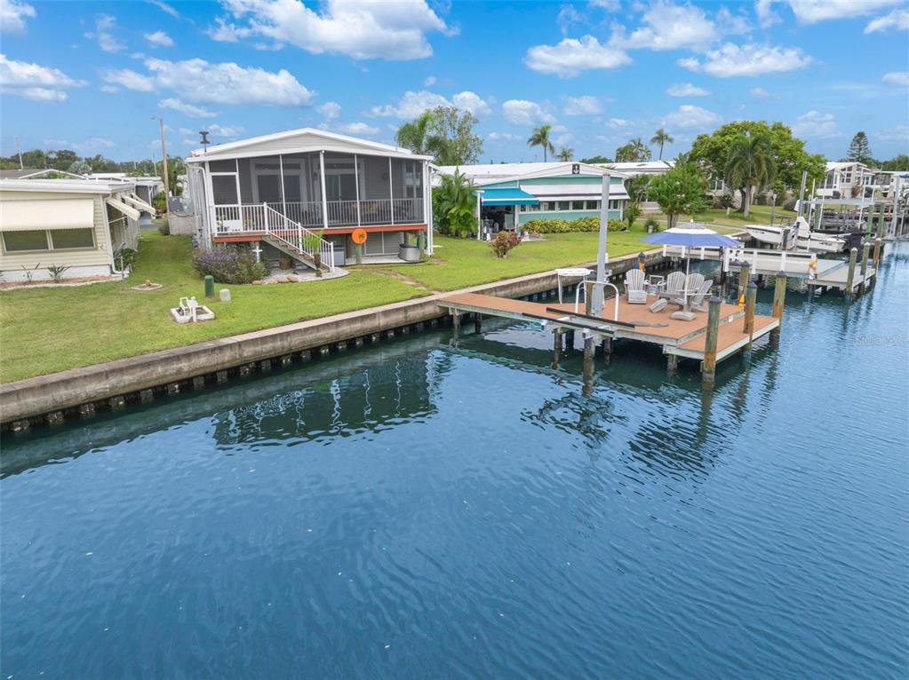A waterfront mobile home features a screened porch, a private dock, and a grassy lawn — 6825 MOUNT ORANGE DRIVE NE UNIT 390, ST PETERSBURG, FL