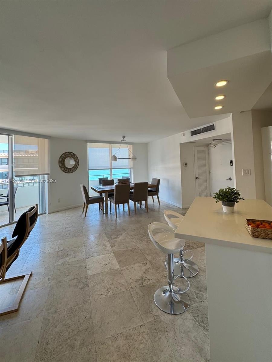 An open-concept living and dining area features light stone flooring and views of the ocean — 5161 E Collins Ave # 1612, Miami Beach FL 33140, MIAMI BEACH, FL