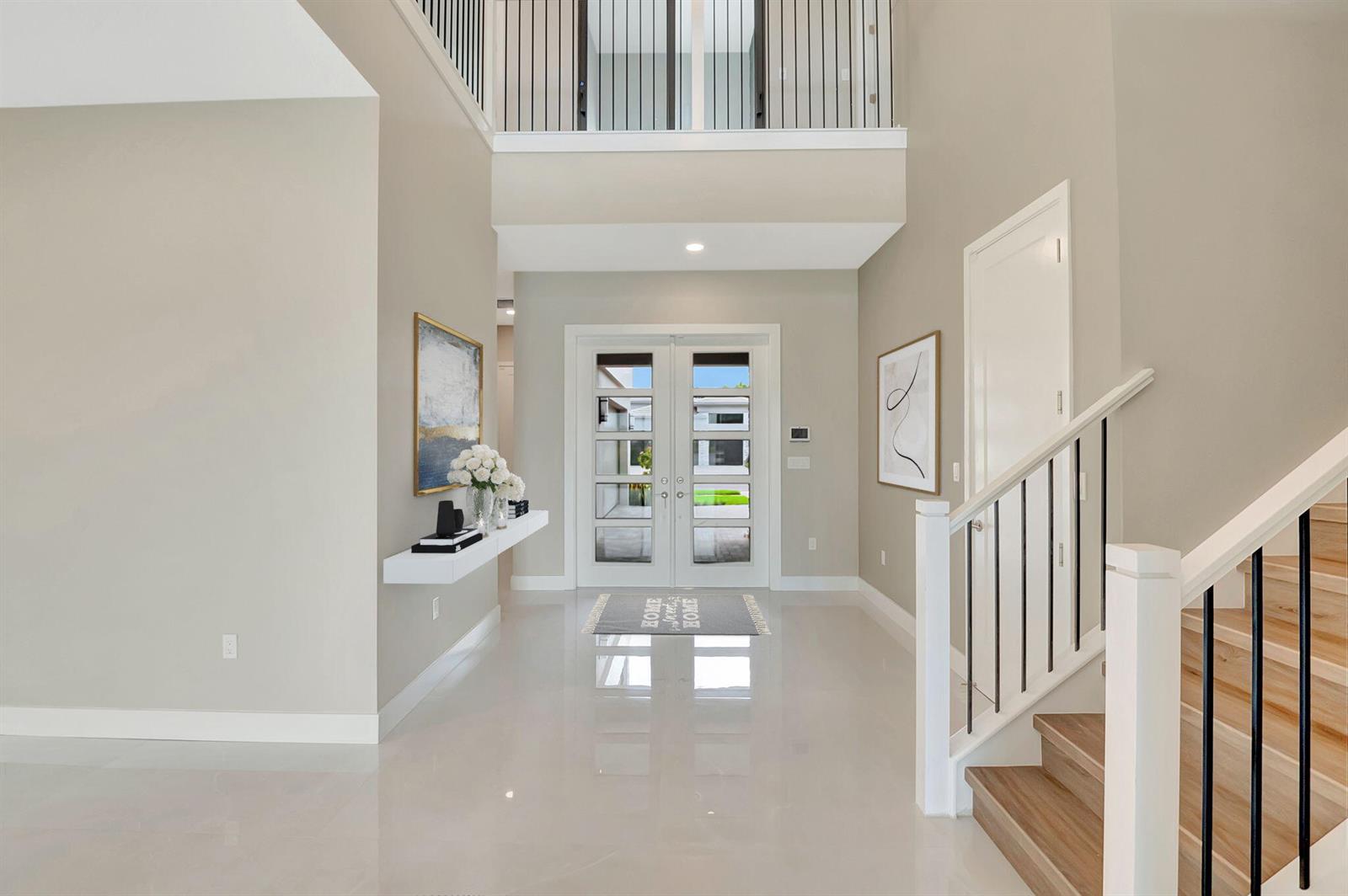 A bright entryway features a double-door entrance, a floating shelf, and a wooden staircase — 20146 Casa De Campo Lane, Boca Raton FL 33434, BOCA RATON, FL