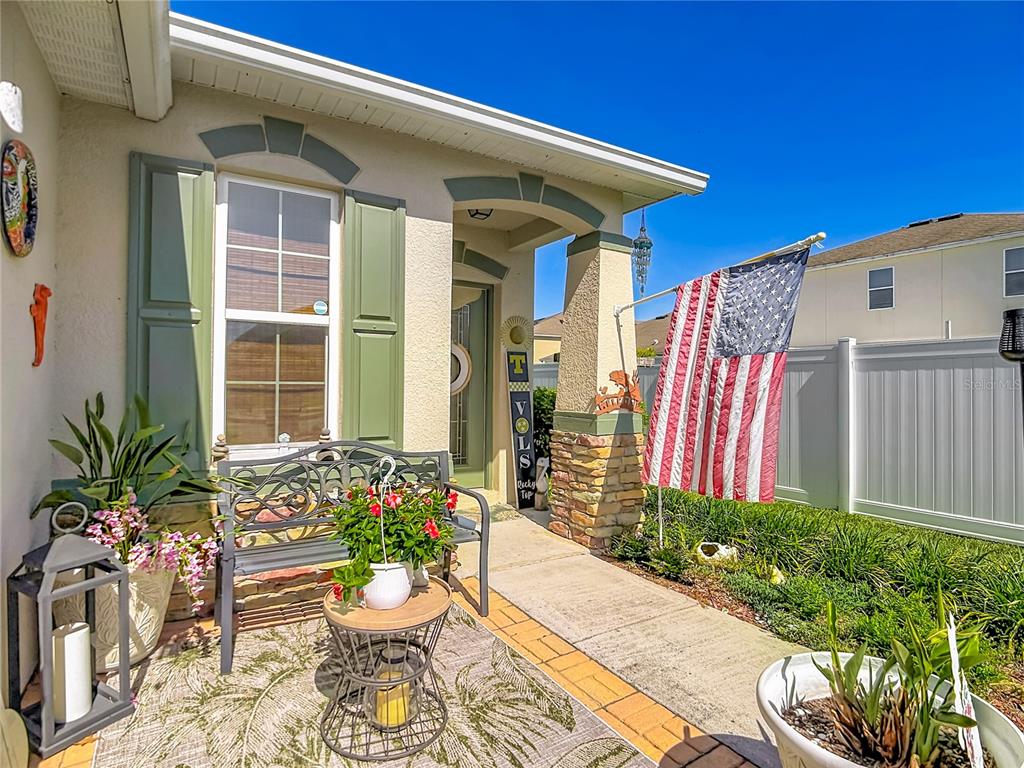 A front porch features a metal bench, a small table, potted plants, and an American flag — 5739 DORNICH DRIVE, AUBURNDALE, FL