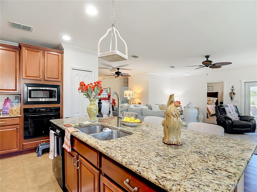 A kitchen island with a granite countertop and sink sits before an open living area — 5739 DORNICH DRIVE, AUBURNDALE, FL