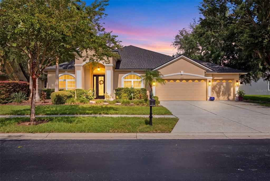 A single-story suburban house with a tan stucco exterior, arched windows, and a three-car garage — 3004 MARBLE CREST DRIVE, LAND O LAKES, FL