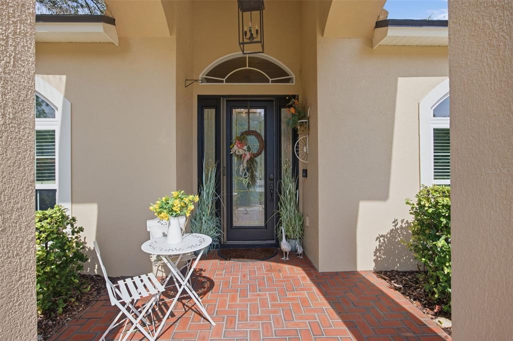 A front entryway features a brick porch, a glass-paneled door, and a small bistro set — 3004 MARBLE CREST DRIVE, LAND O LAKES, FL