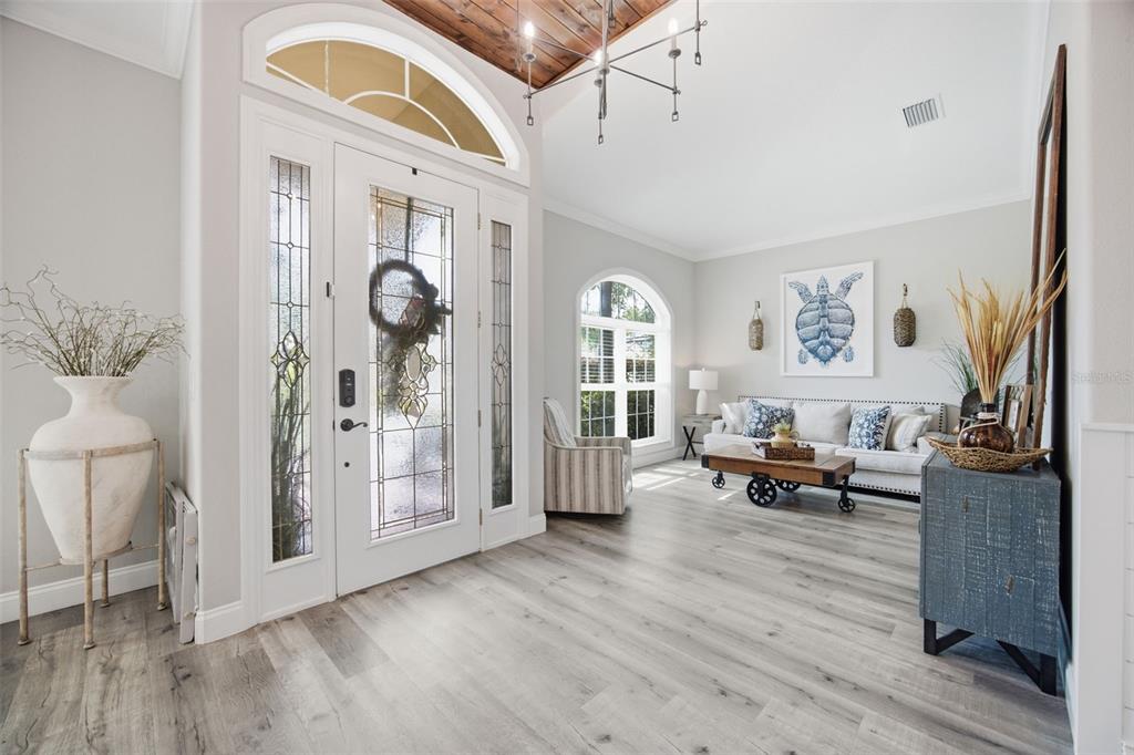 A bright entryway features light wood-look flooring, a glass-paneled front door, and a living area — 3004 MARBLE CREST DRIVE, LAND O LAKES, FL