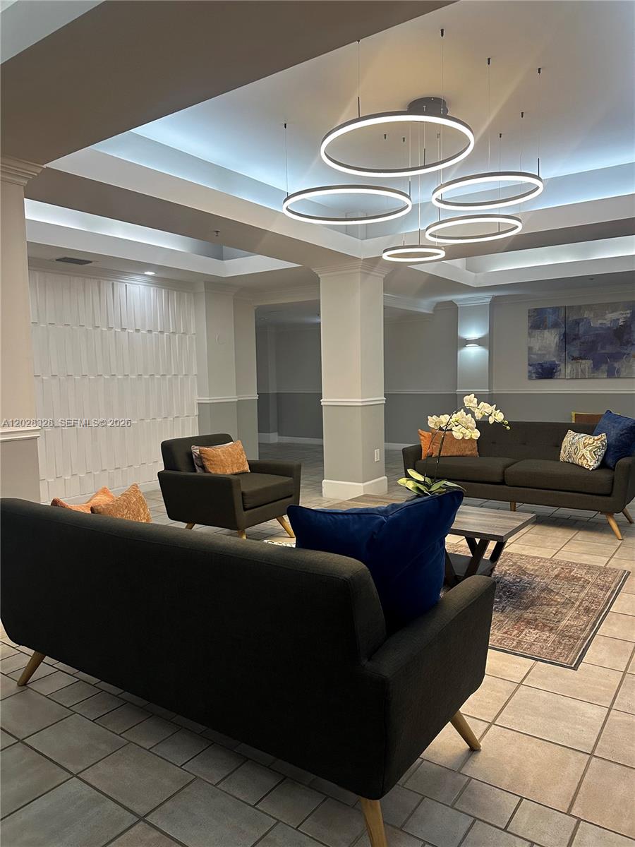 A modern lobby features dark sofas, armchairs, tiled flooring, and a tiered circular pendant light — 9755 NW 52nd St # 219, Doral FL 33178, DORAL, FL