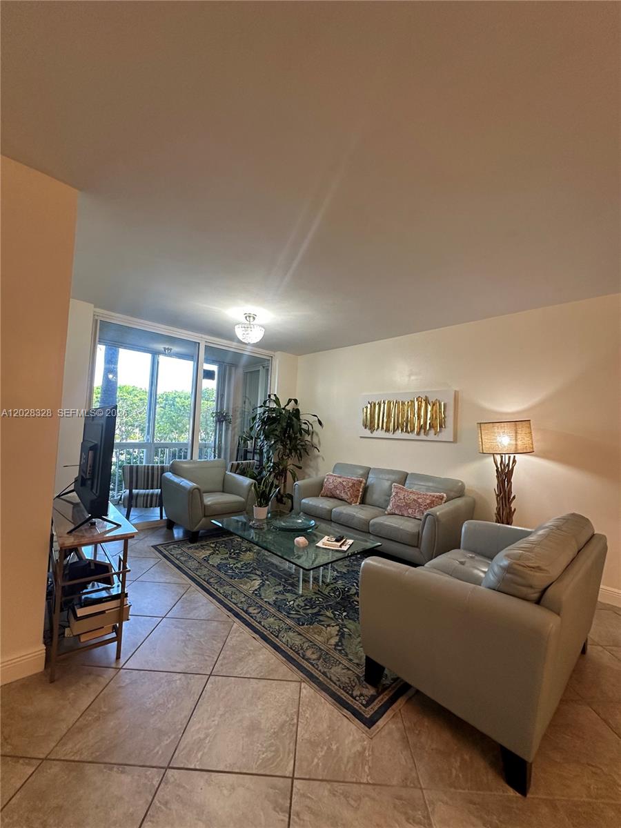 A living room features light-colored leather furniture, a glass coffee table, and tile flooring — 9755 NW 52nd St # 219, Doral FL 33178, DORAL, FL