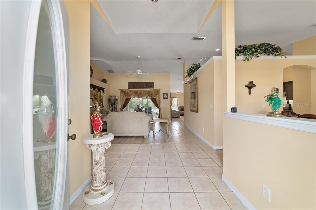 An entryway with tile flooring leads into a living room with vaulted ceilings and curtains — 3465 SE 54TH AVENUE, OCALA, FL