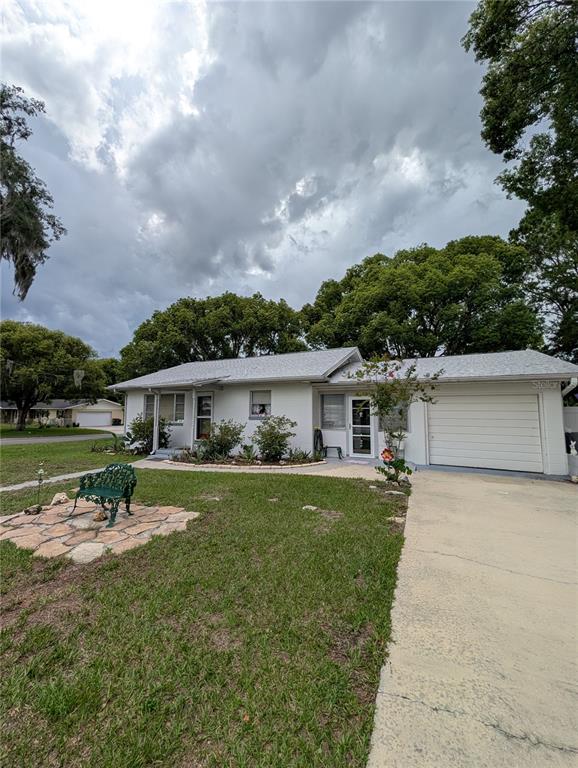A single-story white house with a gray roof, a concrete driveway, and a stone patio — 11240 SE 53RD COURT, BELLEVIEW, FL