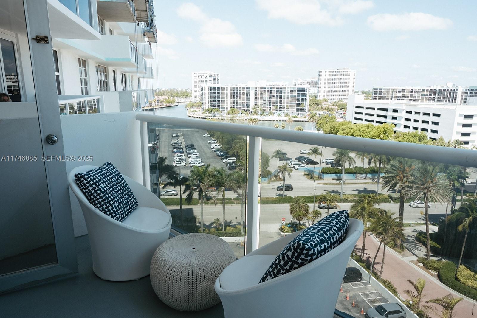 A balcony features two white chairs with patterned pillows and a small round ottoman — 3725 S Ocean Dr # 1019, Hollywood FL 33019, HOLLYWOOD, FL