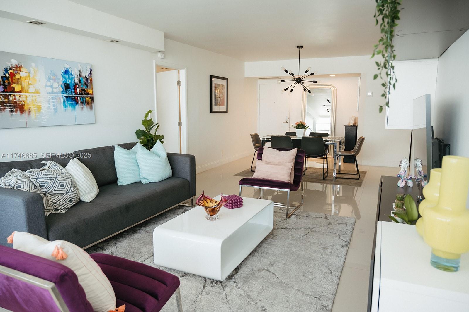 A living room and dining area feature white tile floors, modern furniture, and a chandelier — 3725 S Ocean Dr # 1019, Hollywood FL 33019, HOLLYWOOD, FL