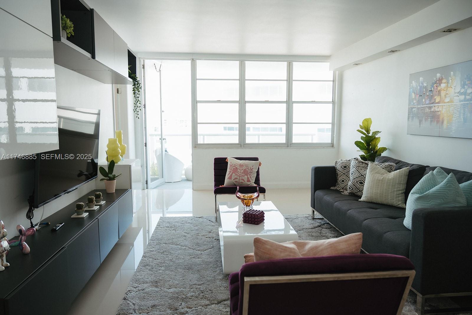 A modern living room features a dark sofa, purple armchairs, and a white coffee table — 3725 S Ocean Dr # 1019, Hollywood FL 33019, HOLLYWOOD, FL