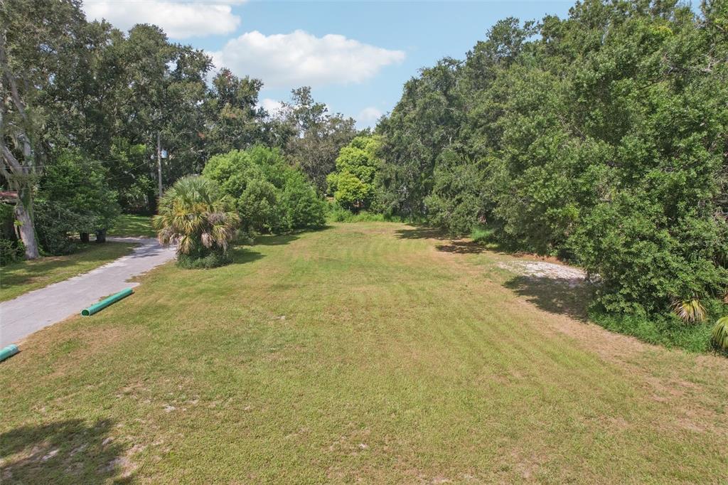 An elevated view of a grassy, rectangular vacant lot surrounded by mature trees — 757 LAKE JESSIE DRIVE, WINTER HAVEN, FL