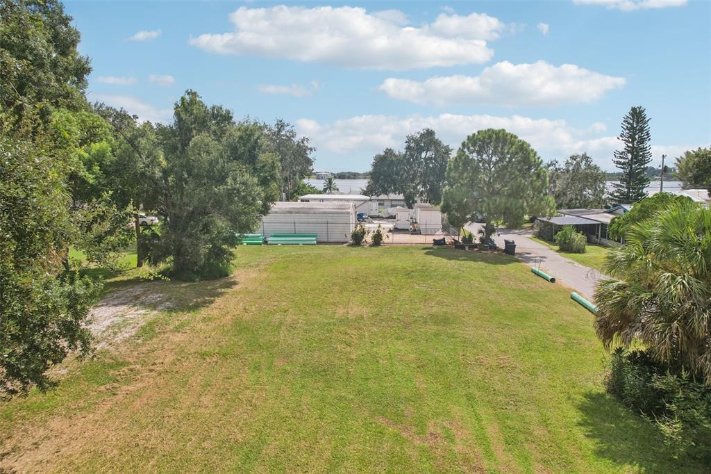 An elevated view of a grassy vacant lot with trees and a nearby water view — 757 LAKE JESSIE DRIVE, WINTER HAVEN, FL