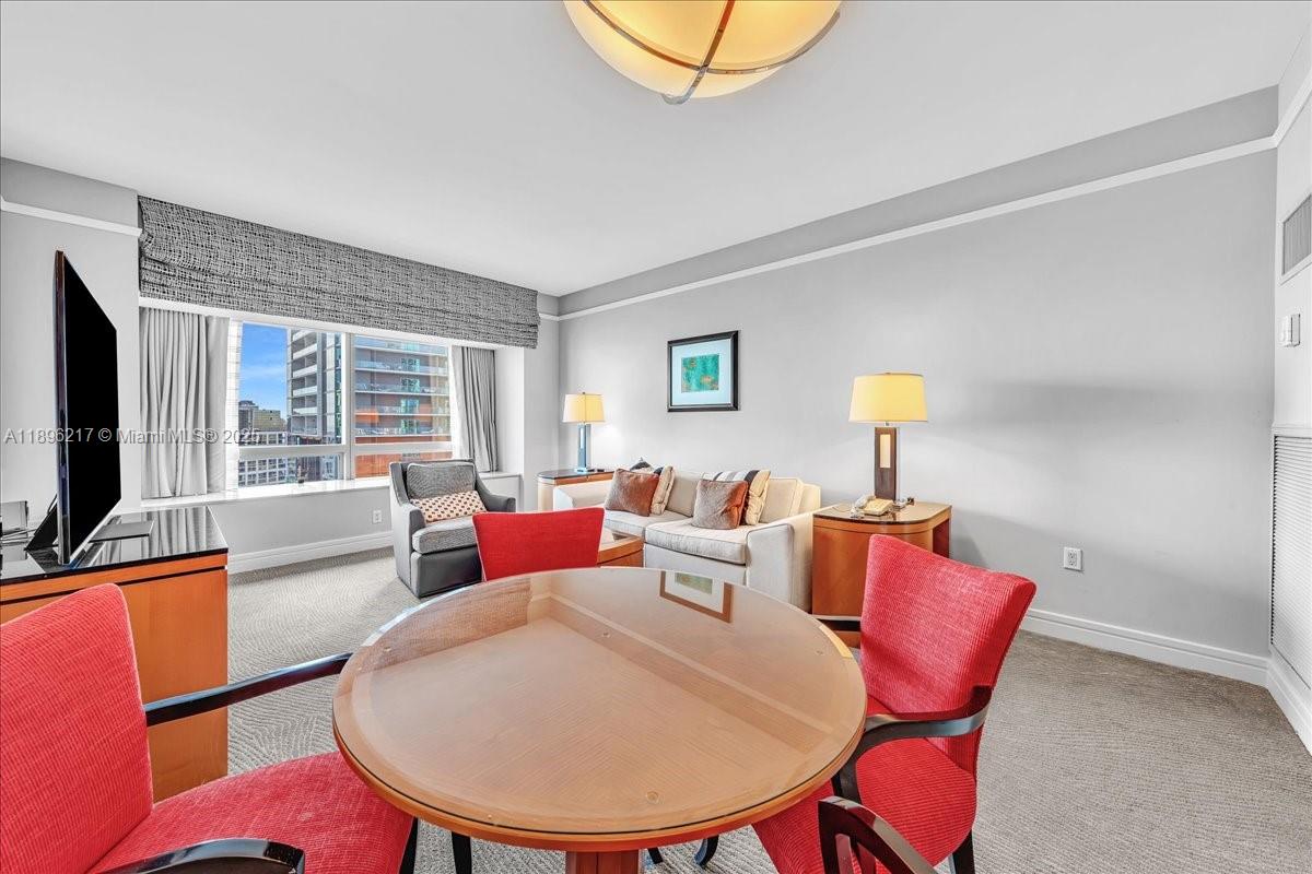 A hotel room features a round dining table, red chairs, and a sofa area — 1435 Brickell Ave # 3603, Miami FL 33131, MIAMI, FL
