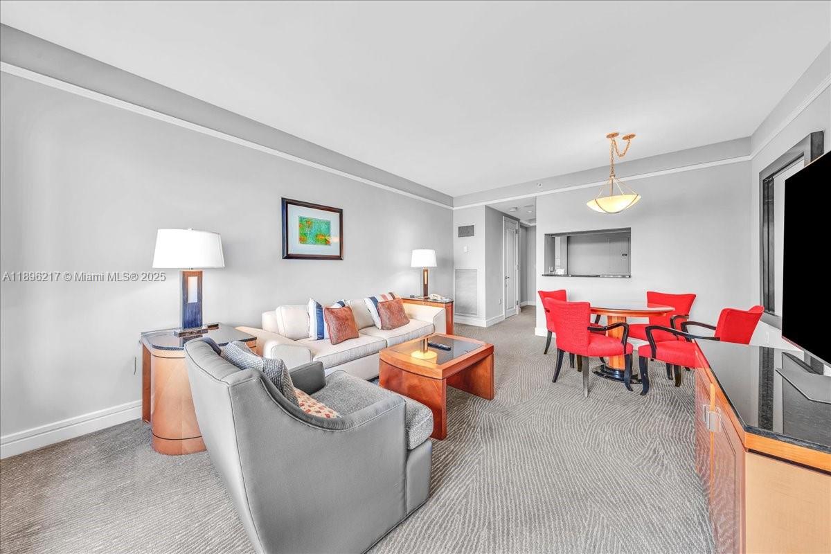 A living and dining area features neutral walls, carpeted floors, and red dining chairs — 1435 Brickell Ave # 3603, Miami FL 33131, MIAMI, FL
