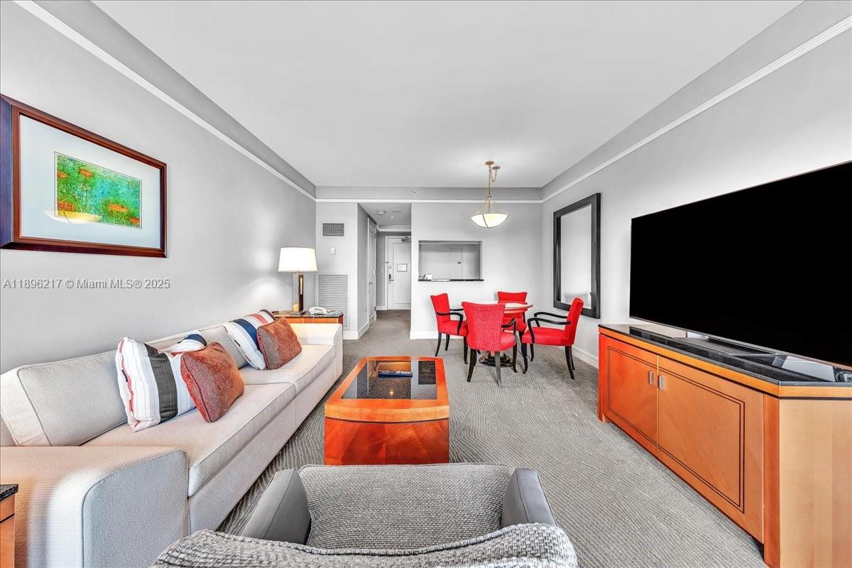 A living room features a sofa, a coffee table, a dining set, and a television — 1435 Brickell Ave # 3603, Miami FL 33131, MIAMI, FL